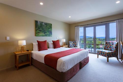 a bedroom with a large bed and a balcony at Distinction Fox Glacier - Te Weheka Boutique Hotel in Fox Glacier