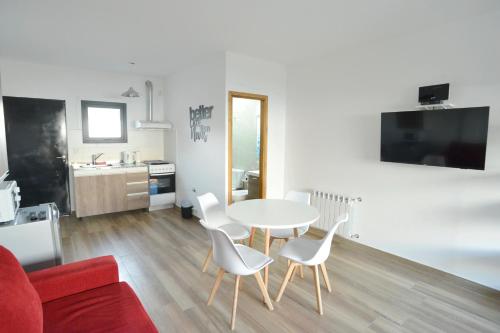 a living room with a table and white chairs at Loft los Ñires in Ushuaia