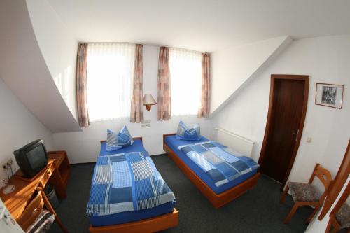 a attic room with two beds and a tv at Wehrstedter Hof in Halberstadt