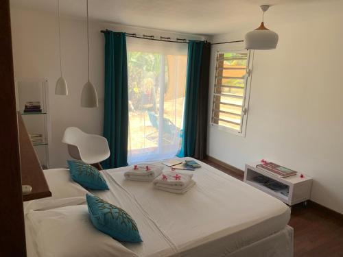 Un dormitorio con una cama con almohadas azules y una ventana en POÉ CÔTÉ LAGON en Bourail