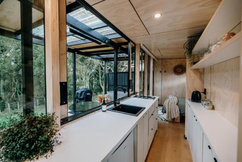a kitchen with a sink and a large window at Blackwood Cabin in Raglan