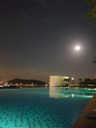 - une piscine la nuit avec la lune dans le ciel dans l'établissement Direct QBM & IKEA *Highfloor Sunrise Seaview Condo, à Bayan Lepas
