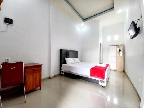 a bedroom with a white bed and a red blanket at Harmony House Syariah near Alun Alun Pati Mitra RedDoorz in Pati