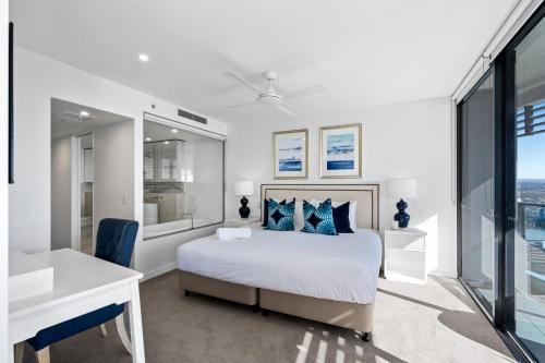 a white bedroom with a bed and a desk at Oracle Resort Broadbeach - gclr in Gold Coast