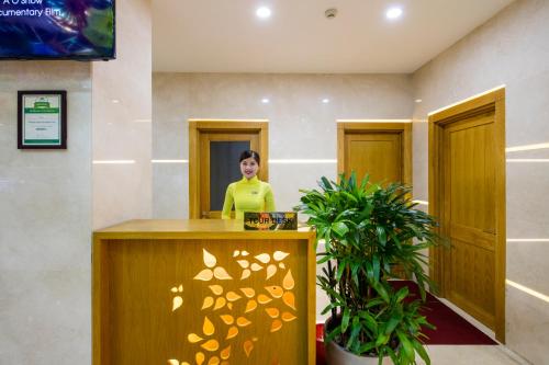 a woman is standing behind a reception desk in a lobby at Paradise Saigon Boutique Hotel & Spa in Ho Chi Minh City