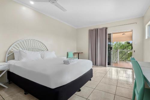 a hotel room with a large bed and a large window at Hotel Tropiq in Cairns