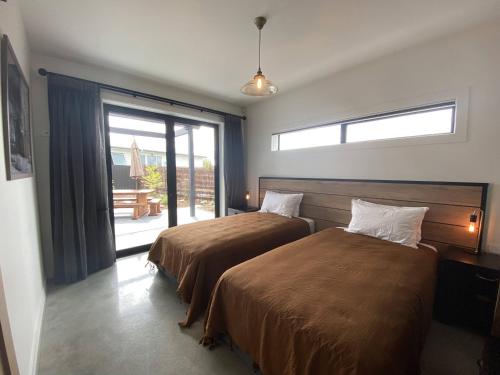 a bedroom with two beds and a large window at Black Stilt Retreat, STUNNING luxury property in Twizel