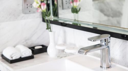 a bathroom sink with a mirror and flowers on it at Marco Polo Xiamen in Xiamen