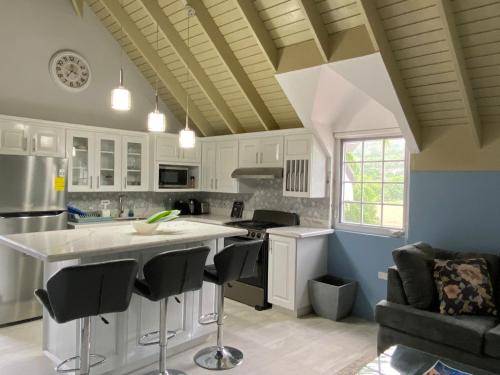 a kitchen with white cabinets and black bar stools at Seacastles by the beach/pool in Montego Bay