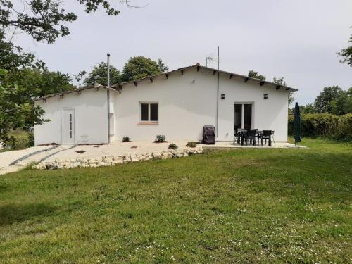 a white house with a picnic table in front of it at Gîte en pleine nature, A la douceur des Chênes in Maubec