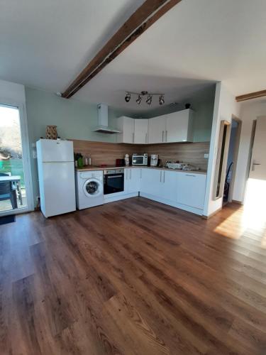 a kitchen with white appliances and a wooden floor at Gîte en pleine nature, A la douceur des Chênes in Maubec