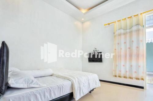 Tempat tidur dalam kamar di Griya Rahayu Guesthouse Mitra RedDoorz near Jatim Park 2 Batu