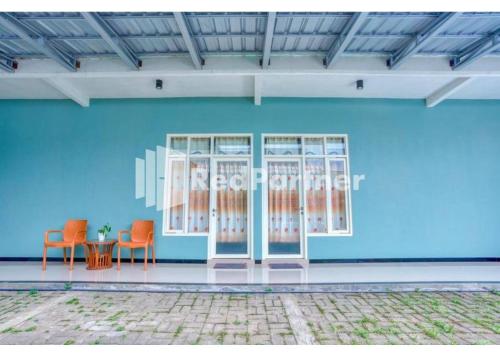 a blue room with two chairs and a table at Griya Rahayu Guesthouse Mitra RedDoorz near Jatim Park 2 Batu in Tlekung