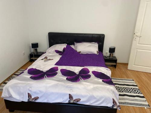 Un dormitorio con una cama con mariposas moradas. en Private House Citadela Tg.Mures, en Târgu Mureș