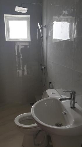 a bathroom with a toilet and a sink and a window at Rodrigo Building 4 in Boralesgamuwa