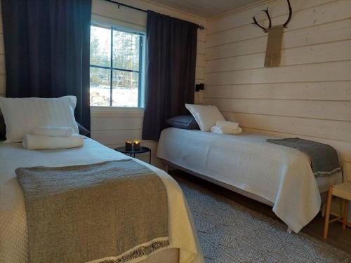 a bedroom with two beds and a window at Villa Vasa - new luxury villa next to lake in Meltaus