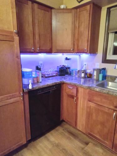 a kitchen with wooden cabinets and a black dishwasher at Outdoor Hot Tub and Cozy King Bed in Lansing