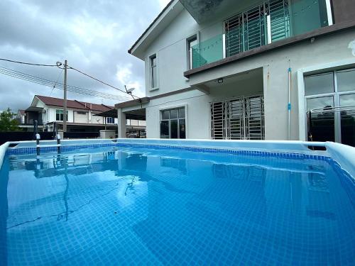 a large blue swimming pool in front of a house at De Nadia Homestay in Port Dickson