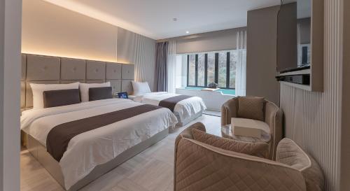a hotel room with two beds and a chair at Denbasta forest Hotel in Busan