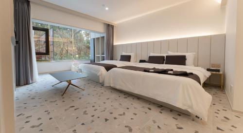 a bedroom with two beds and a large window at Denbasta forest Hotel in Busan