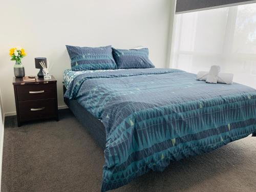 a bedroom with a bed with a blue comforter at Auckland Homestay-Ensuite Room, near Airport,Free Parking in Auckland