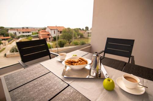 a table with a bowl of food and cups of coffee at Luxury apartment Grotta with sea view and swimming pool in Premantura
