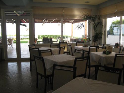 a restaurant with white tables and chairs and a patio at Alma Hotel in Kamena Vourla