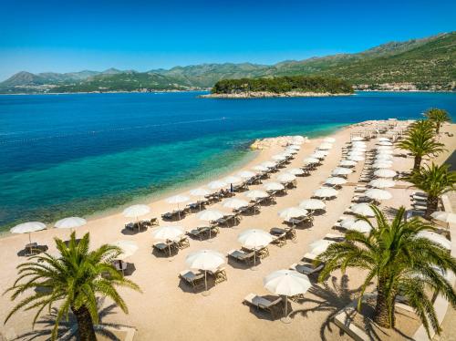 a beach with a bunch of umbrellas and the ocean at President Hotel, Valamar Collection in Dubrovnik