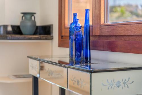 three blue bottles sitting on top of a glass table at Villa Riviera in Costa d'en Blanes