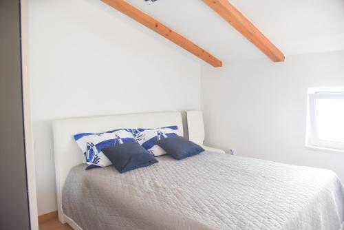 a white bedroom with a bed with blue pillows at Aptartment - Istrian Dream with swimming pool in Peroj