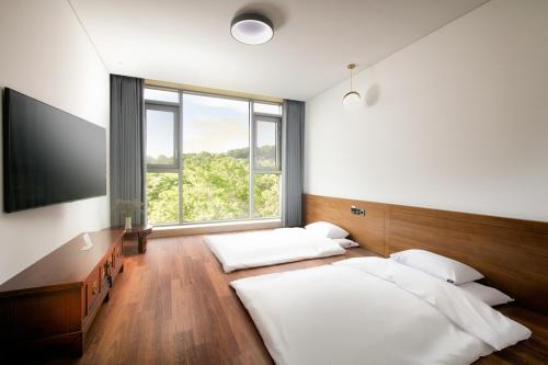 a bedroom with two beds and a large window at Daon Hotel in Jeonju