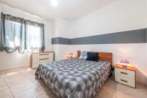 a bedroom with a bed and two dressers and two windows at Casa Vacanza Casi in Villasimius