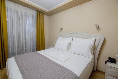 a bedroom with a white bed and a window at Christi's Hotel Borova in Korçë