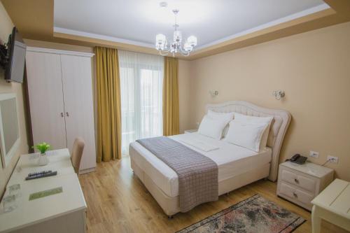 a bedroom with a white bed and a chandelier at Christi's Hotel Borova in Korçë