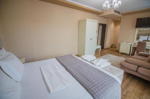 a bedroom with a large white bed and a chair at Christi's Hotel Borova in Korçë