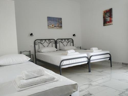 a white bedroom with two beds and a bench at Koukounari Studios in Neos Marmaras