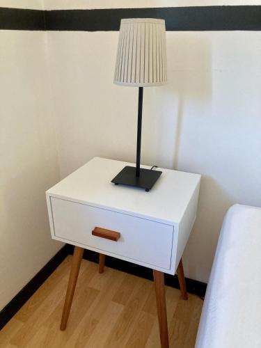 a white bedside table with a lamp on it at Villa Câline chambres d'hôtes in Vesseaux
