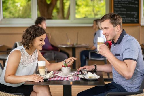 a man and woman sitting at a table with drinks at Hotel Bellevue Tlapak in Poděbrady