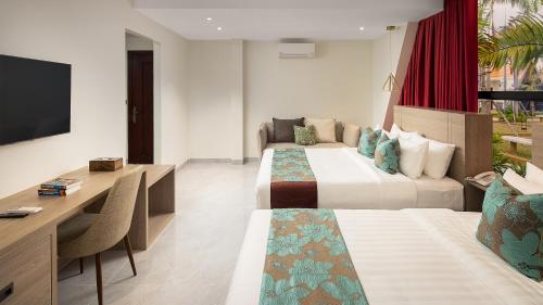 a hotel room with two beds and a desk at Vakara Hotel Kep in Kep