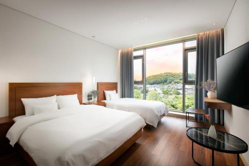 a hotel room with two beds and a large window at Daon Hotel in Jeonju