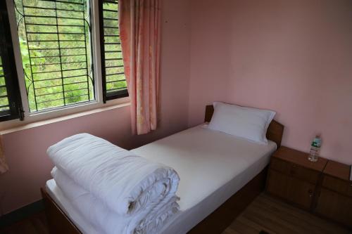 a small bed in a room with two windows at Hotel Mount Paradise in Nagarkot