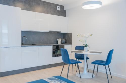 kuchnia ze stołem i niebieskimi krzesłami w obiekcie Apartament Sapphire Rogowo Pearl w mieście Mrzeżyno
