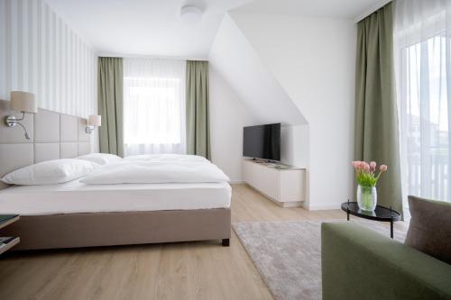 a white bedroom with a bed and a tv at Landhaus Bad Gleichenberg in Bad Gleichenberg