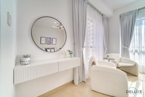 ein weißes Zimmer mit einem Spiegel und weißen Stühlen in der Unterkunft Impeccable 2BR at Bahar 2 JBR by Deluxe Holiday Homes in Dubai