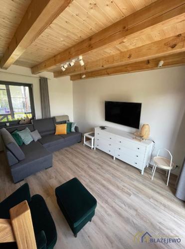 a living room with a couch and a flat screen tv at Domki Błażejewo in Łukęcin
