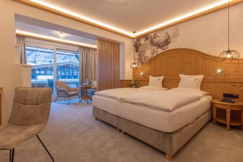 um quarto de hotel com uma cama grande e uma cadeira em Hotel St. Georg em Mayrhofen