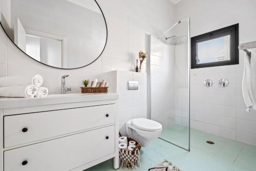 a white bathroom with a toilet and a mirror at כרמית Aria boutique in Kramim