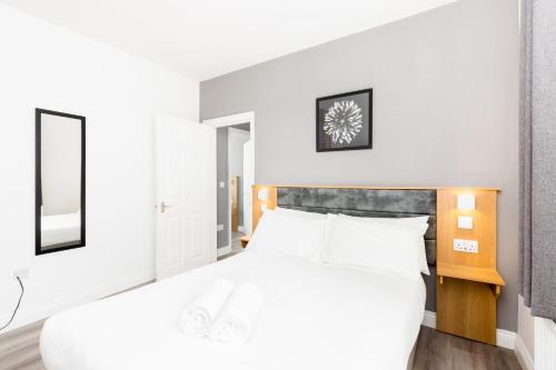 a bedroom with a white bed and a mirror at Marvel Apartments Leamington Spa in Leamington Spa