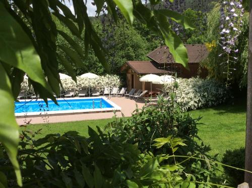 a swimming pool in a garden with umbrellas at Residence Hauserhof in Rodengo