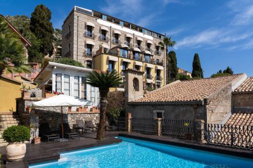 un hotel con piscina di fronte a un edificio di Hotel Villa Carlotta a Taormina